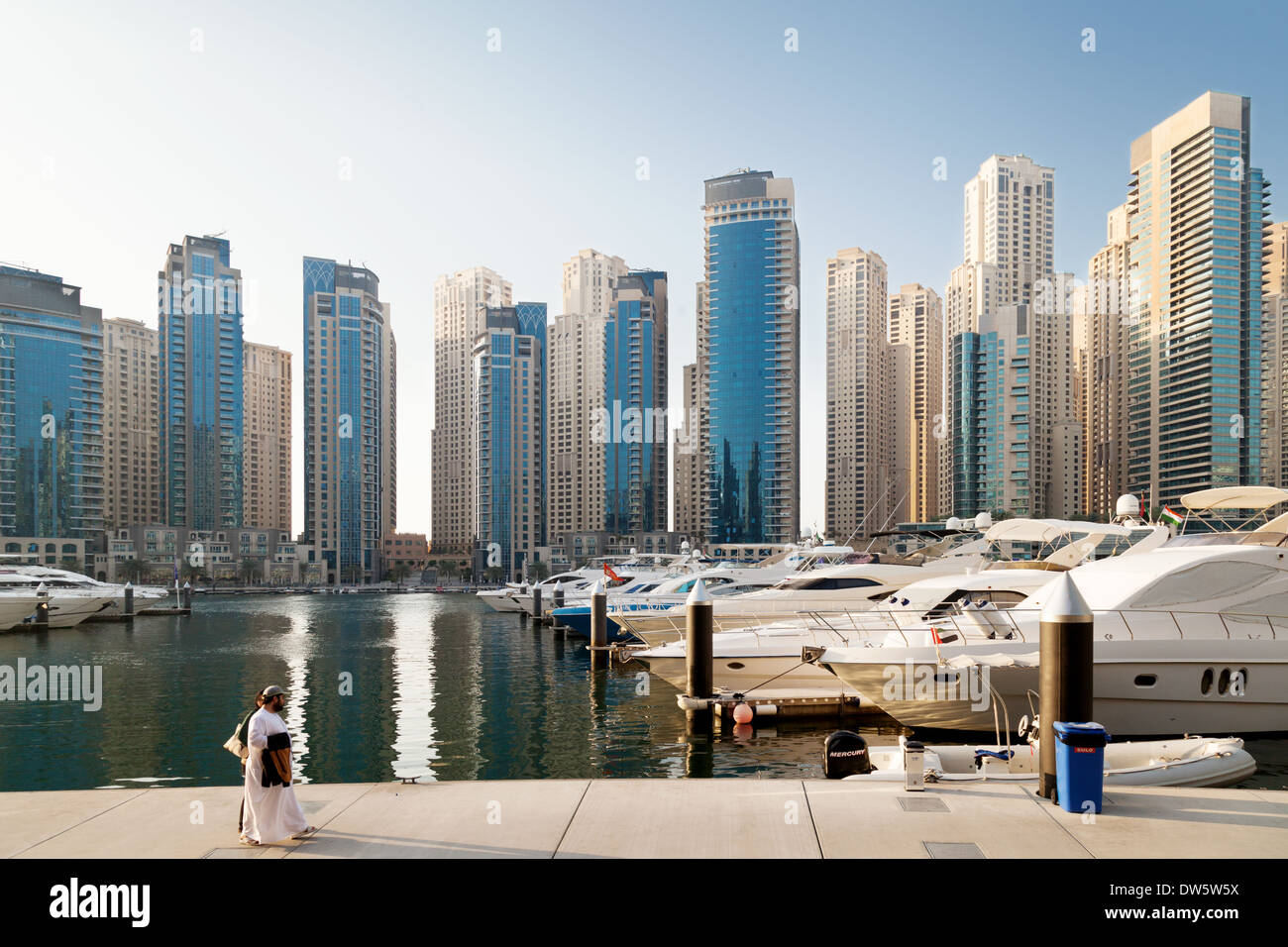 An arab couple walking in Dubai Marina, the Jumeirah Towers area, Dubai skyscrapers and skyline, UAE, United Arab Emirates Stock Photo