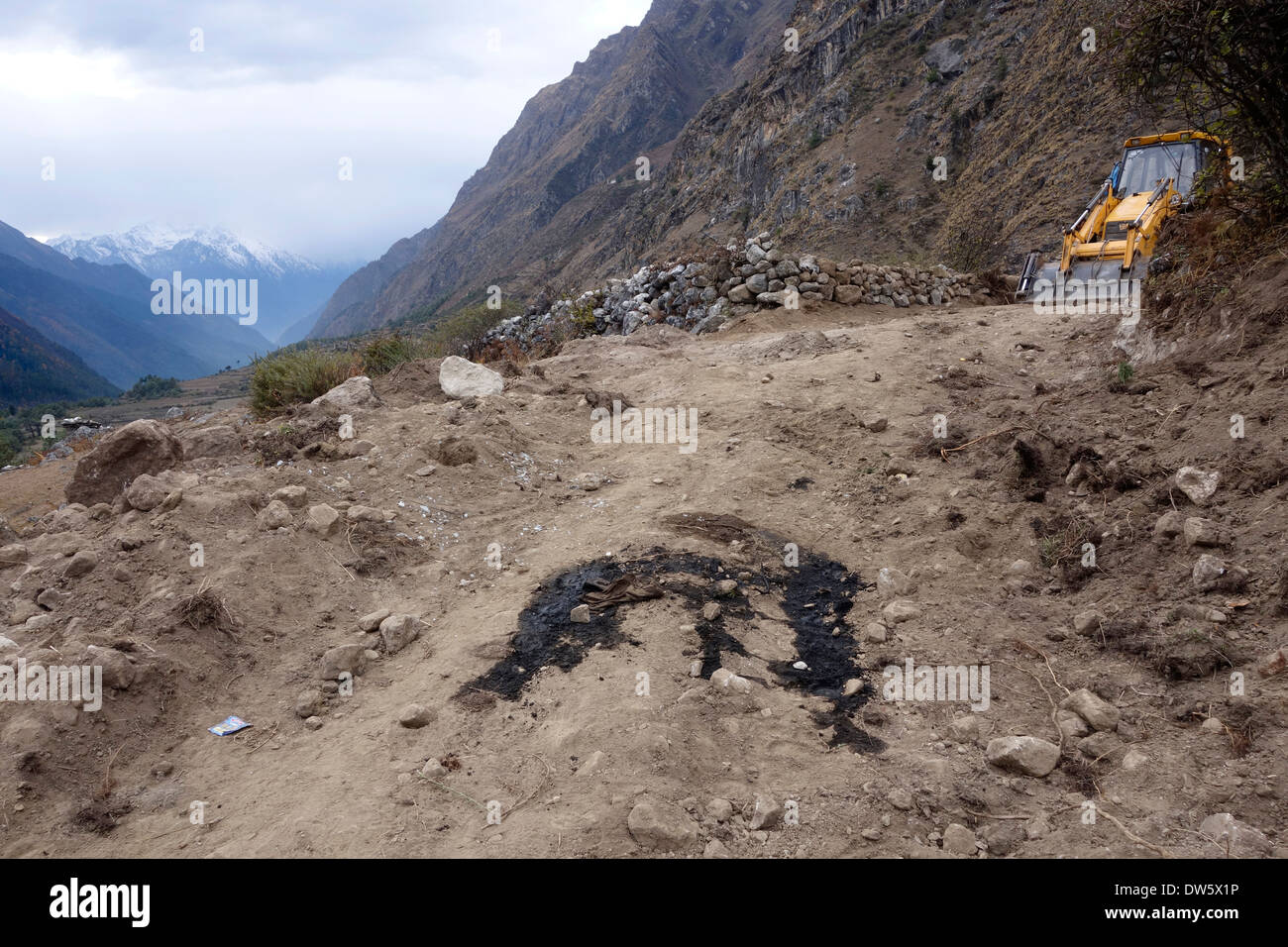 Excavator and spilled motor oil on a controversial new road in the Tsum Valley, Nepal. Stock Photo