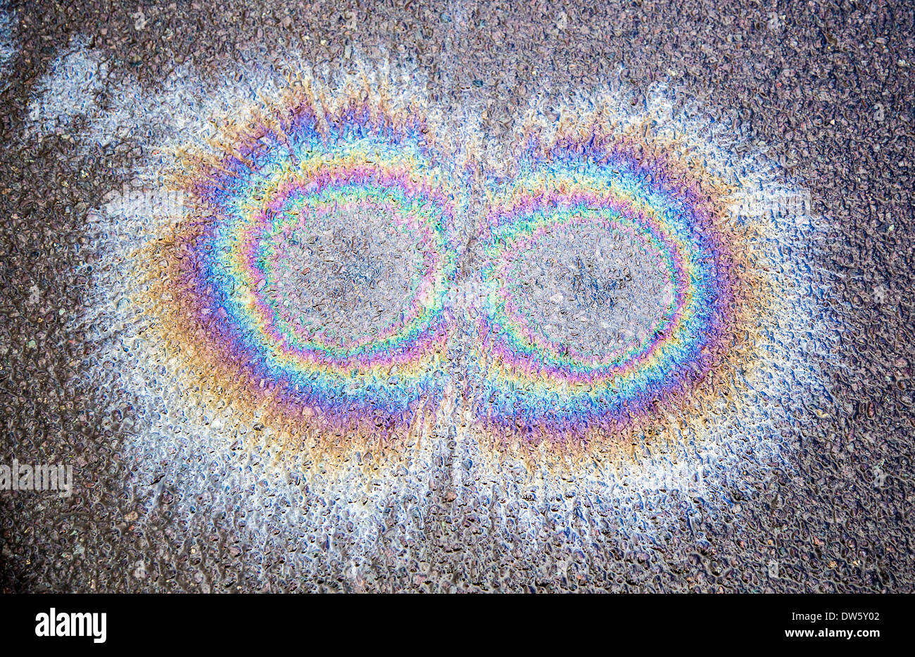 Oil spots on wet Tarmac road forming rainbow interference patterns Stock Photo