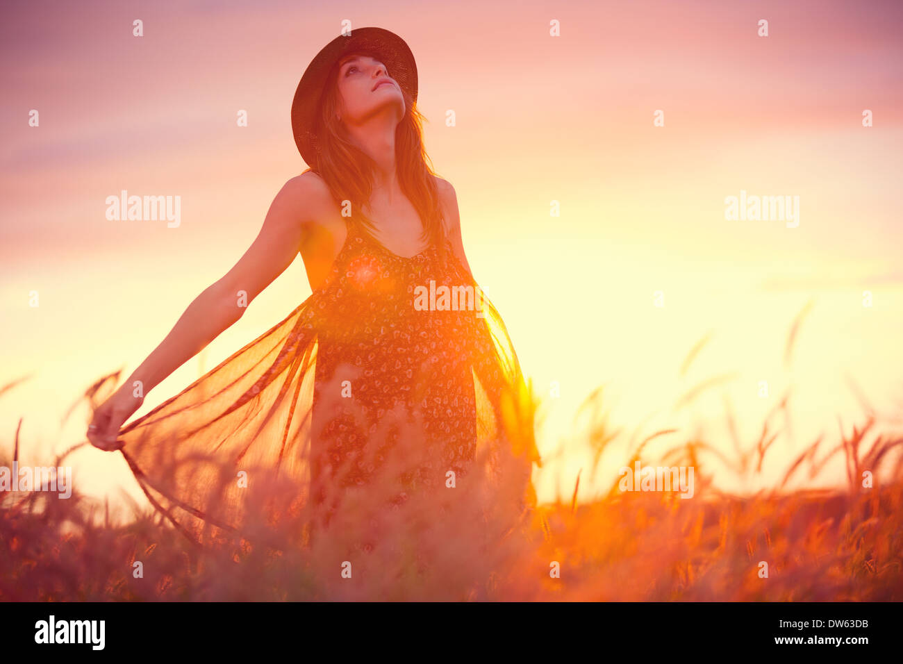 Beautiful woman in golden field at sunset, Fashion lifestyle, Vibrant color, Backlit warm tones Stock Photo