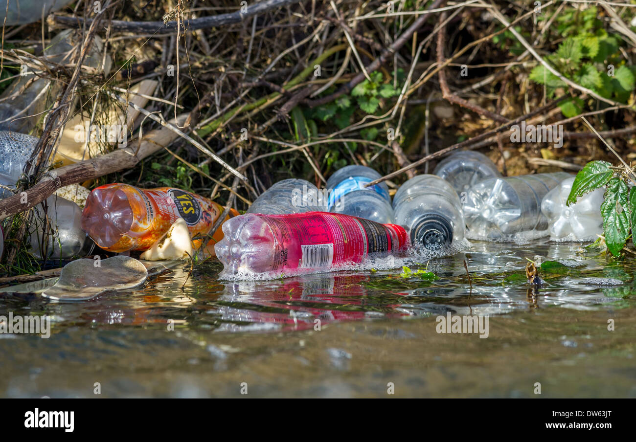 Discarded plastic bottles pollute the banks of a river. Stock Photo