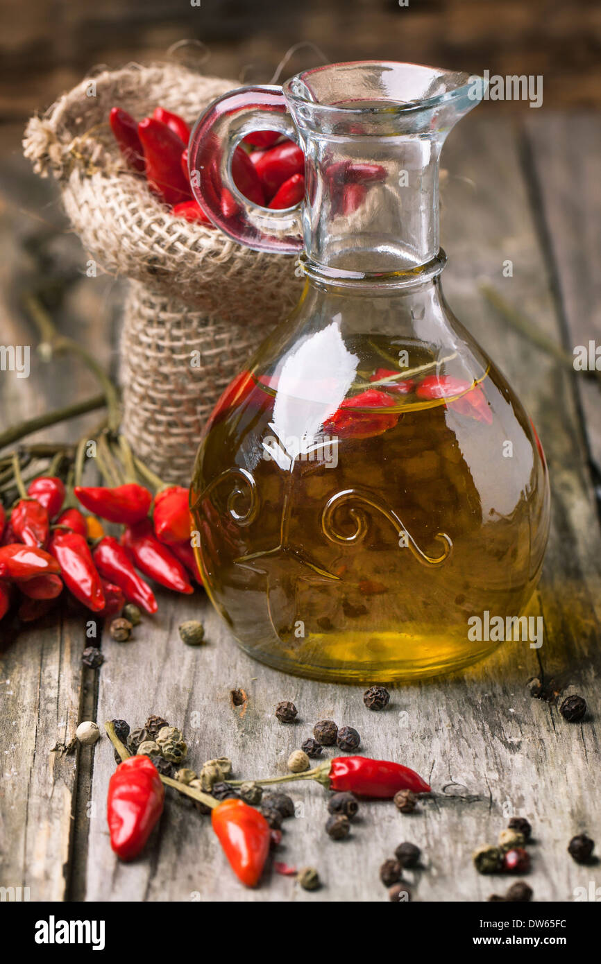 Glass bottle of olive oil with red hot chili peppers over old wooden background Stock Photo Alamy