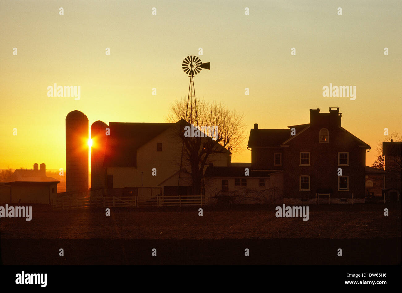 Sunset between silos at Amish farm windmill farmhouse silo Stock Photo