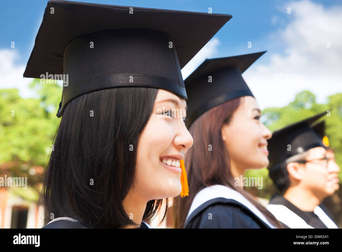 smiling female college graduate standing with classmate on campus Stock Photo