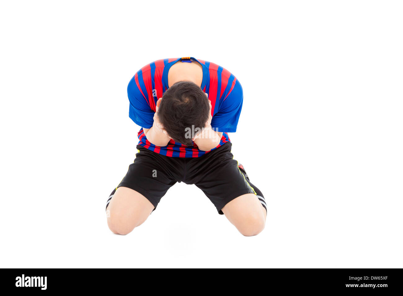 agitated soccer player kneel down and  cover his face to cry in studio Stock Photo