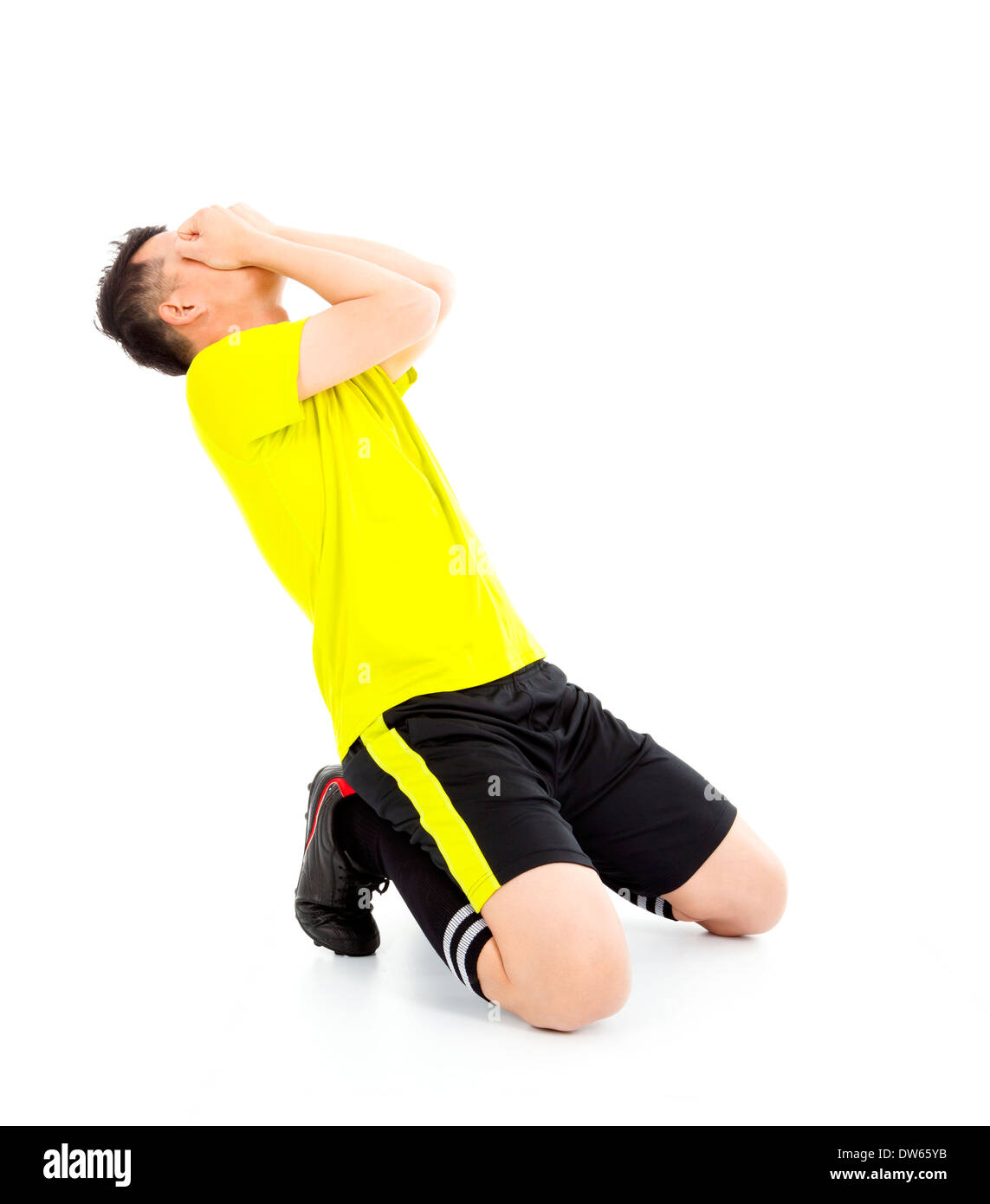 Upset  or excited soccer player kneeling down in studio Stock Photo