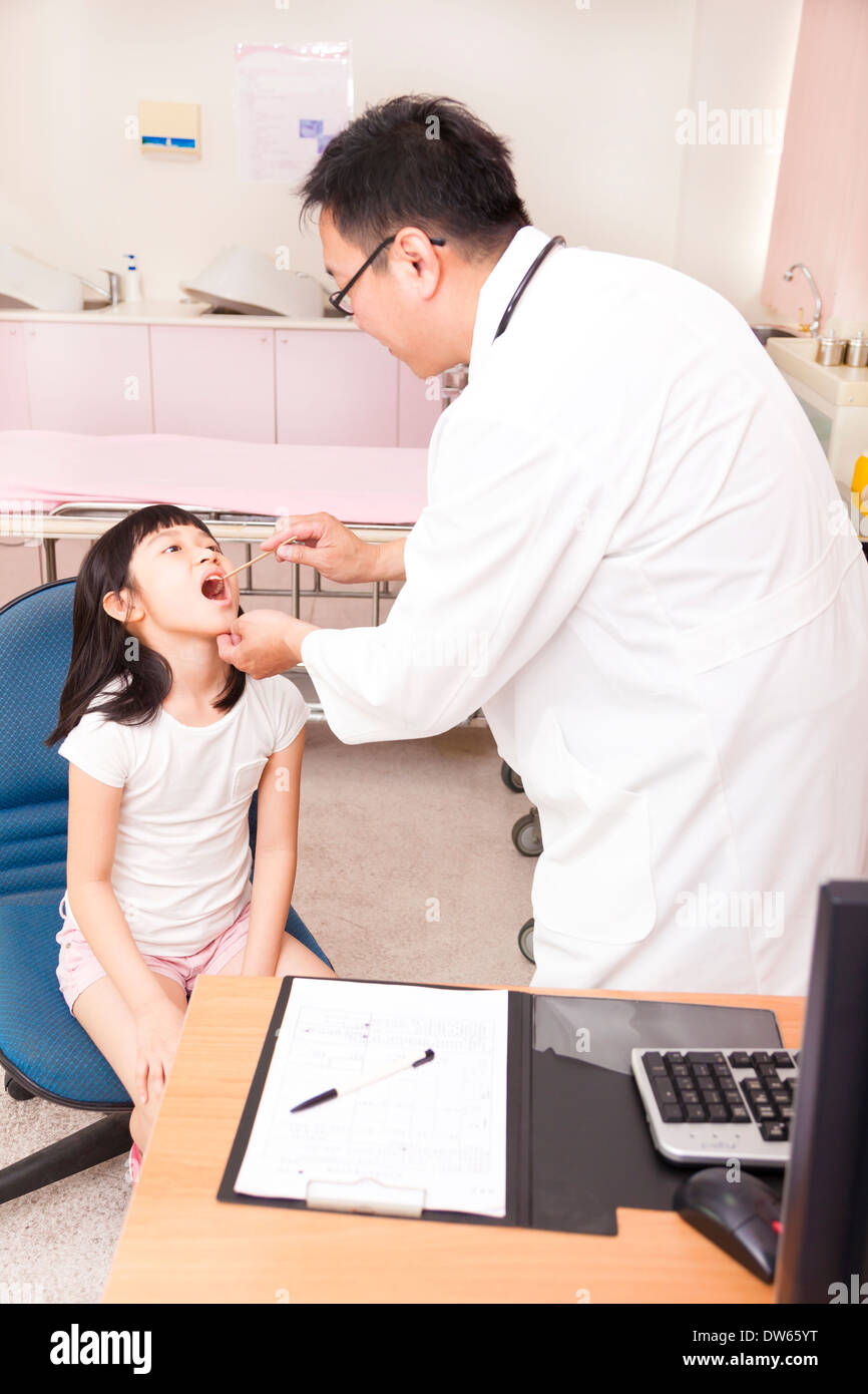 pediatrician examining  kid throat with  tongue depressor in clinic Stock Photo