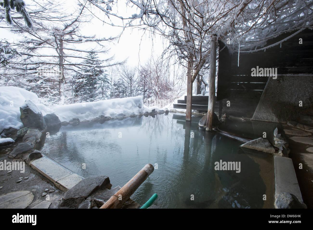 A rotenburo outdoors onsen hot spring in winter and surrounded by snow. Image taken in Nagano, Japan Stock Photo