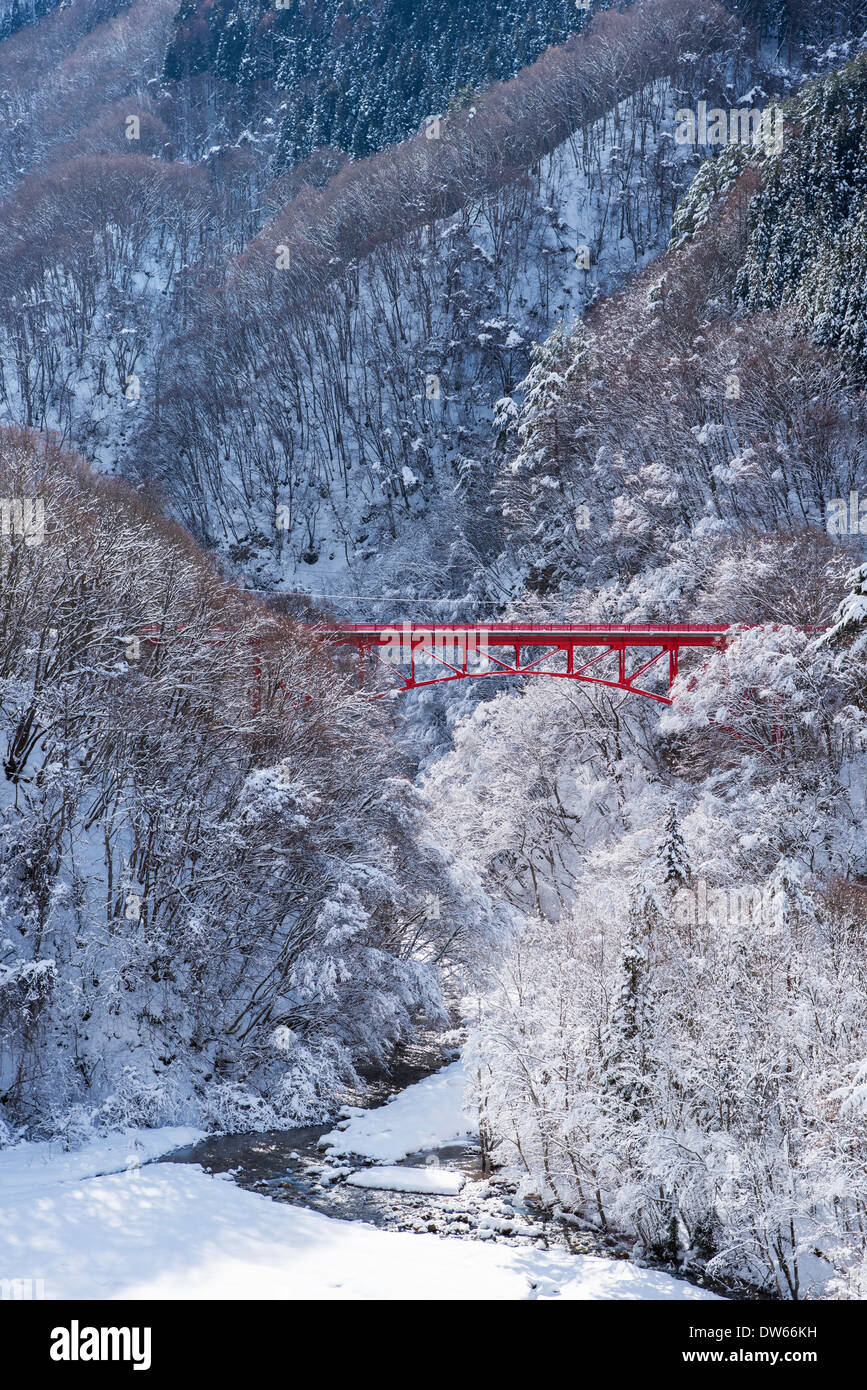 A red bridge spanning a snow covered valley and tress near Yamada Onsen in Nagano, Japan Stock Photo