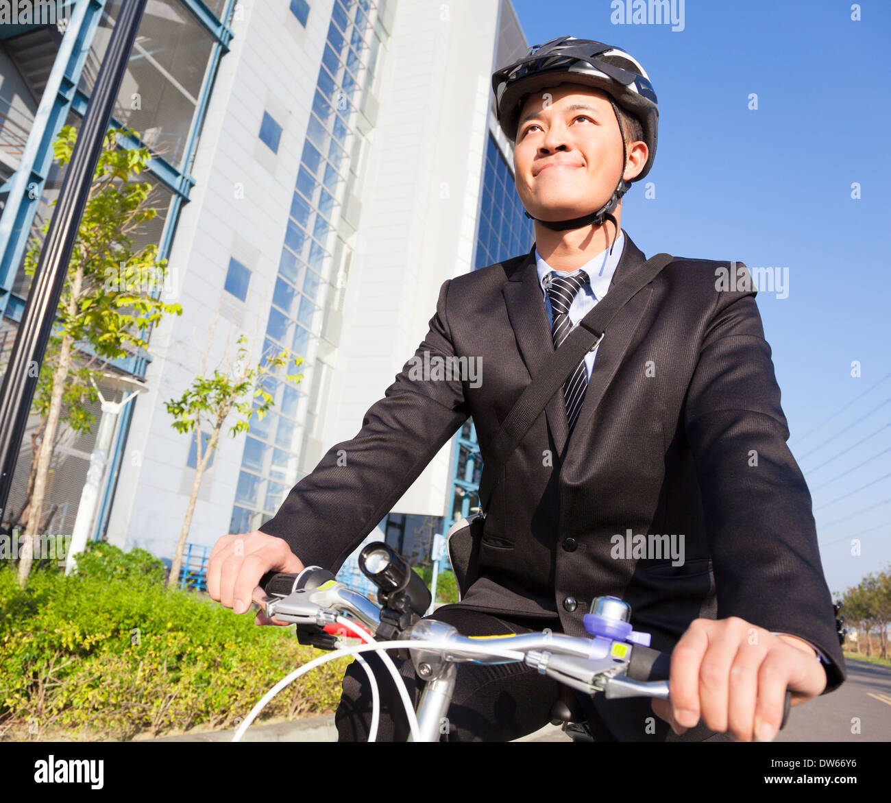 asian smiling businessman riding a bicycle to workplace Stock Photo
