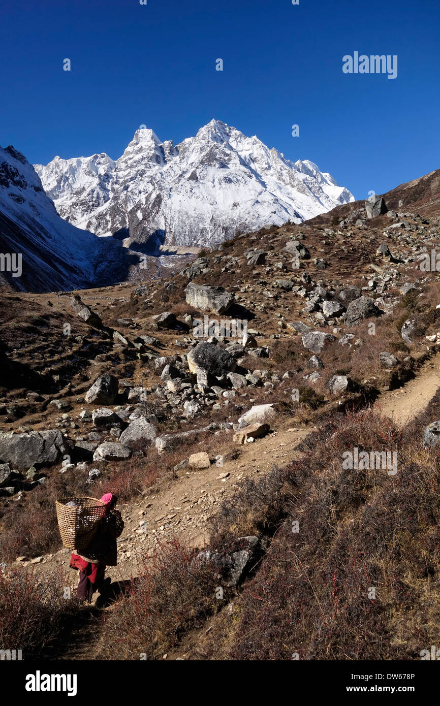Woman carrying basket of goods on a trail in the Manaslu region of Nepal. Stock Photo