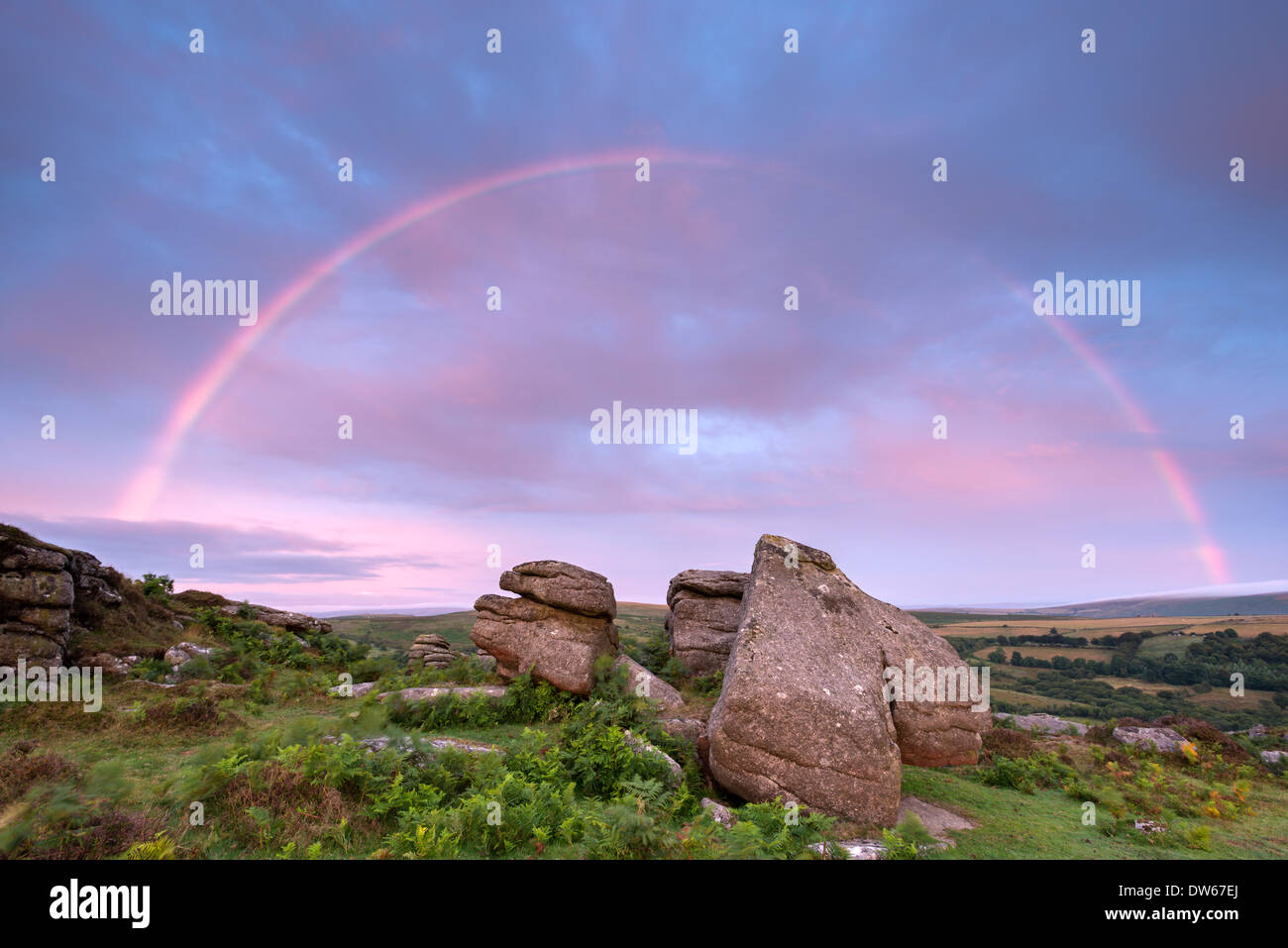 Rainbow over Holwell Tor at sunrise, Dartmoor, Devon, England. Summer (August) 2013. Stock Photo