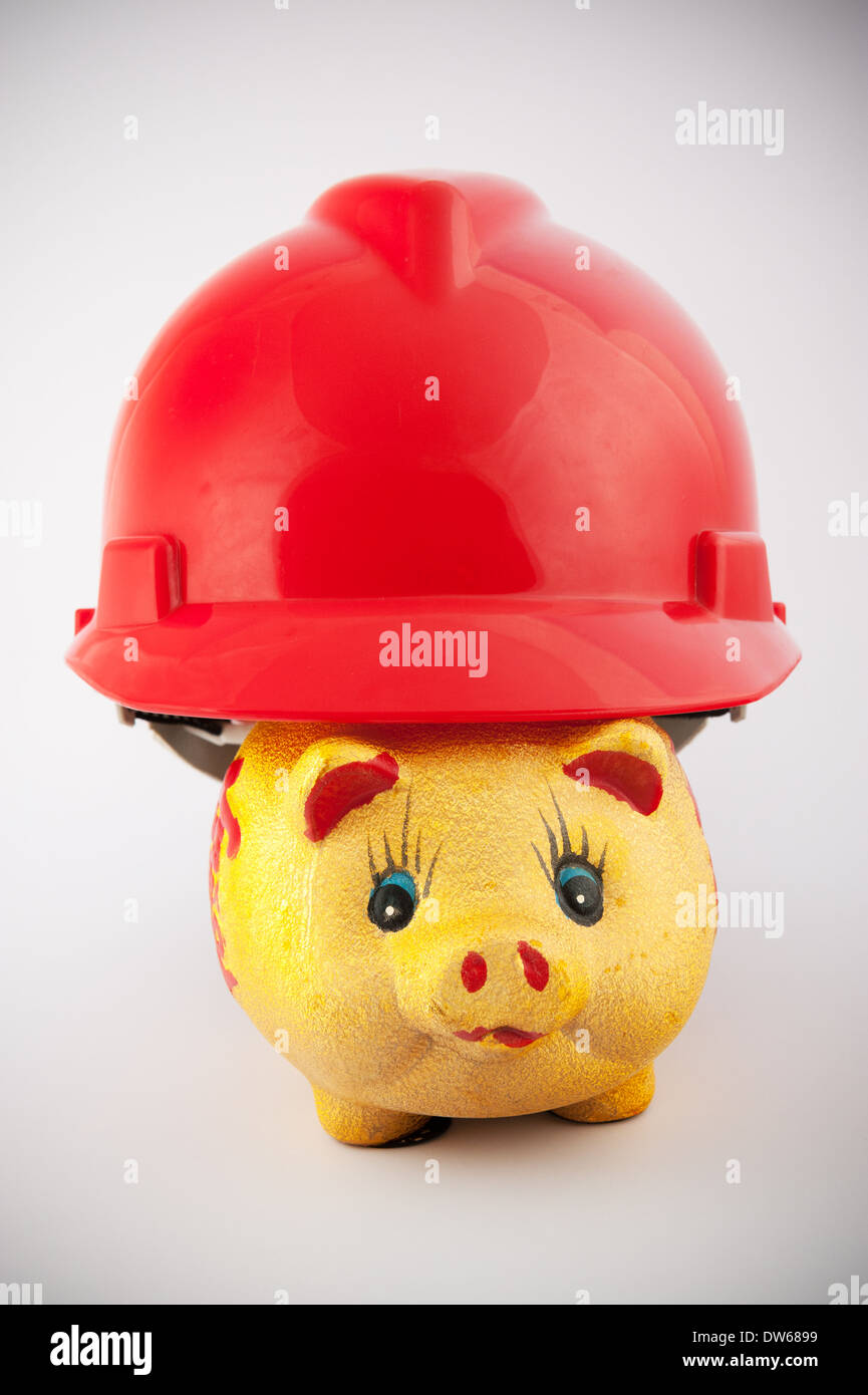 Piggy bank hiding in a safety helmet Stock Photo