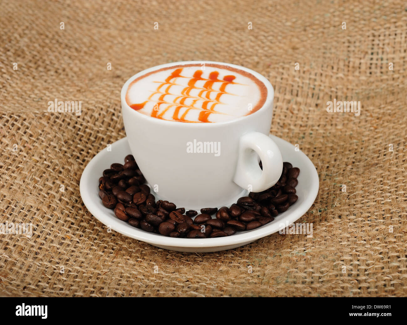 Cappuccino with coffee beans on jute background Stock Photo