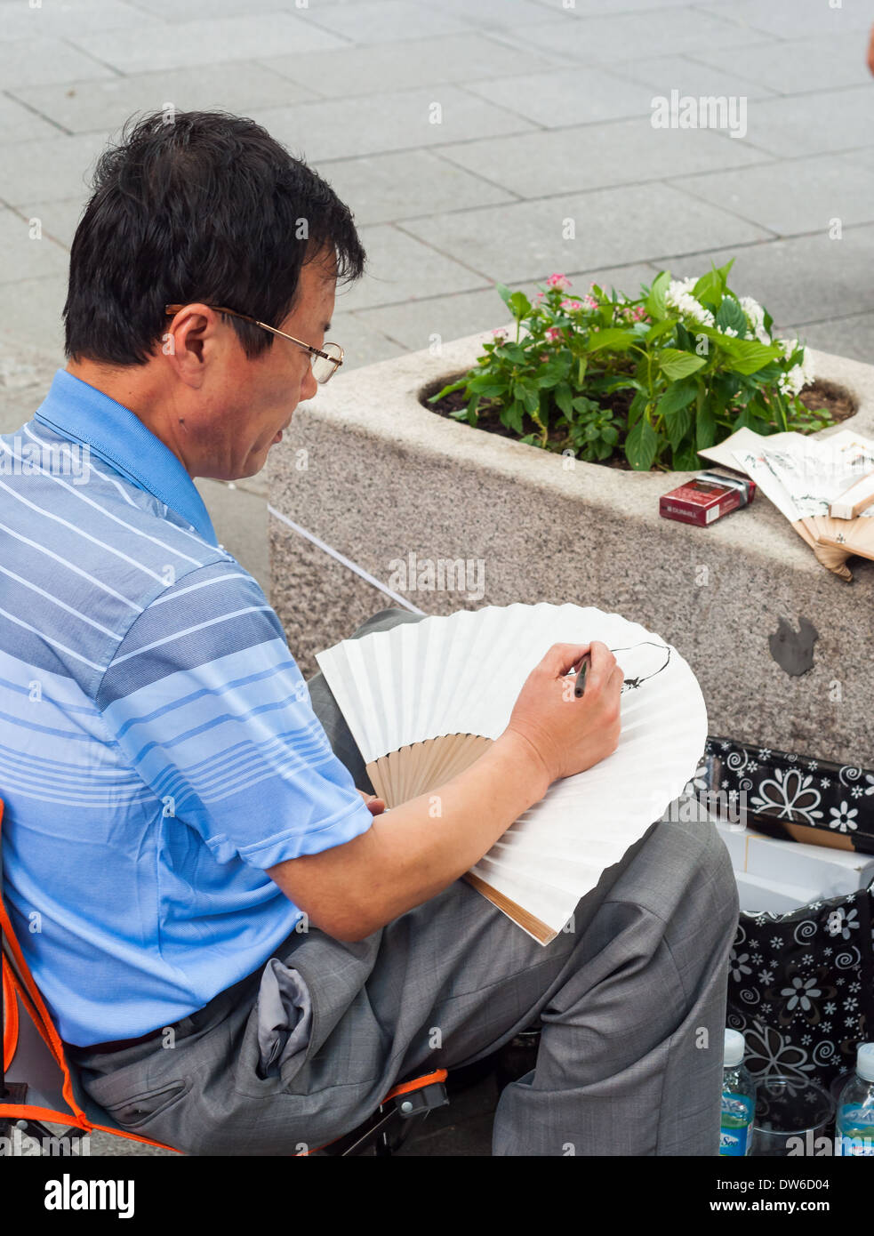 A street artist paints folding fans for sale in Insadong, Seoul. Stock Photo