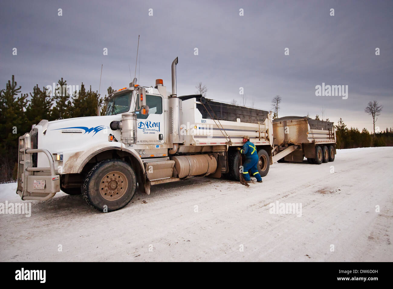 A Canadian truck driver putting chains on the tyres in snowy weather Stock Photo