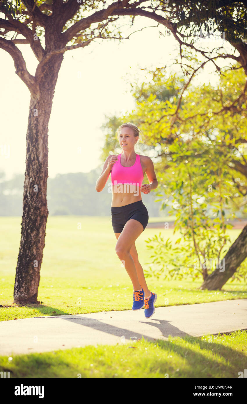 Athletic woman running in park in the early morning Stock Photo