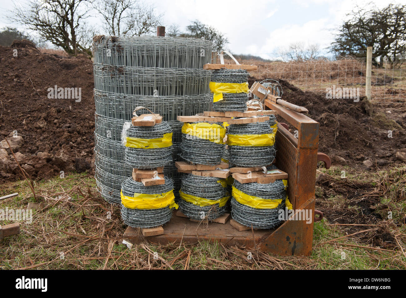 200 metre rolls of High tensile grade A barbed wire and wire fencing on a tractor cradle attachment Stock Photo
