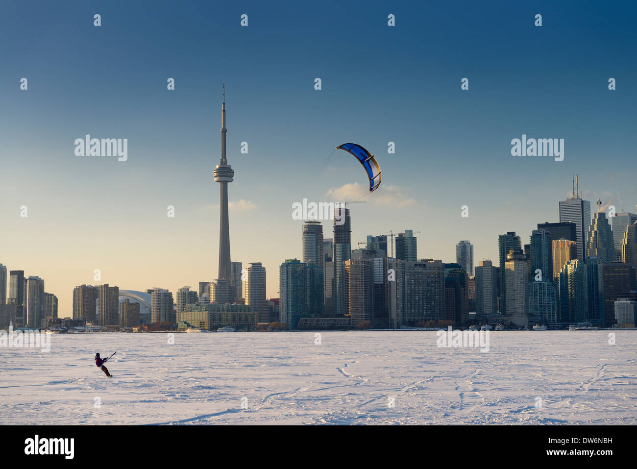 Young man parasail snowboarding on frozen Lake Ontario with Toronto city skyline in winter Stock Photo