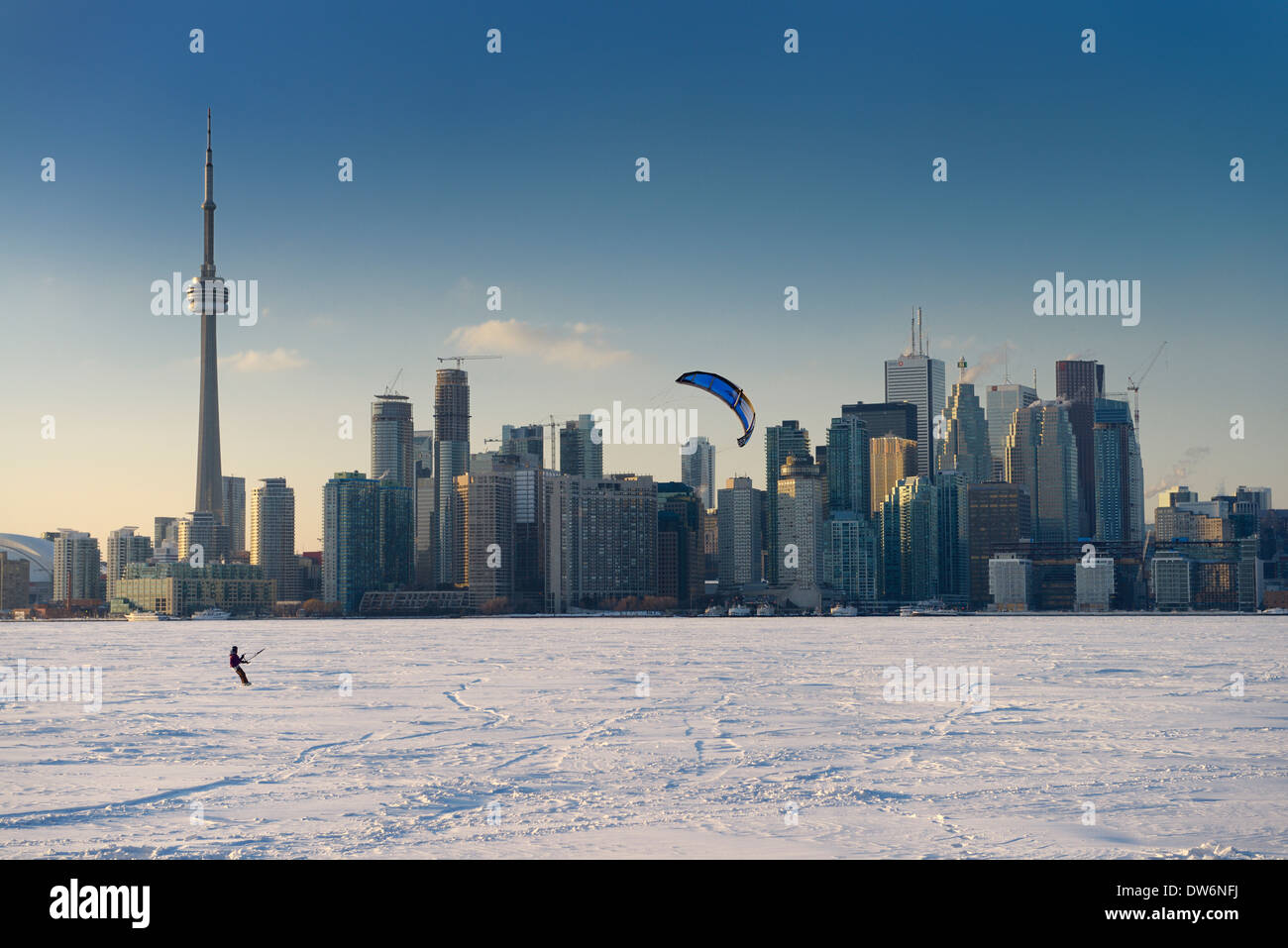Young man snowkiting with snowboard on frozen Lake Ontario with Toronto city skyline in winter Stock Photo