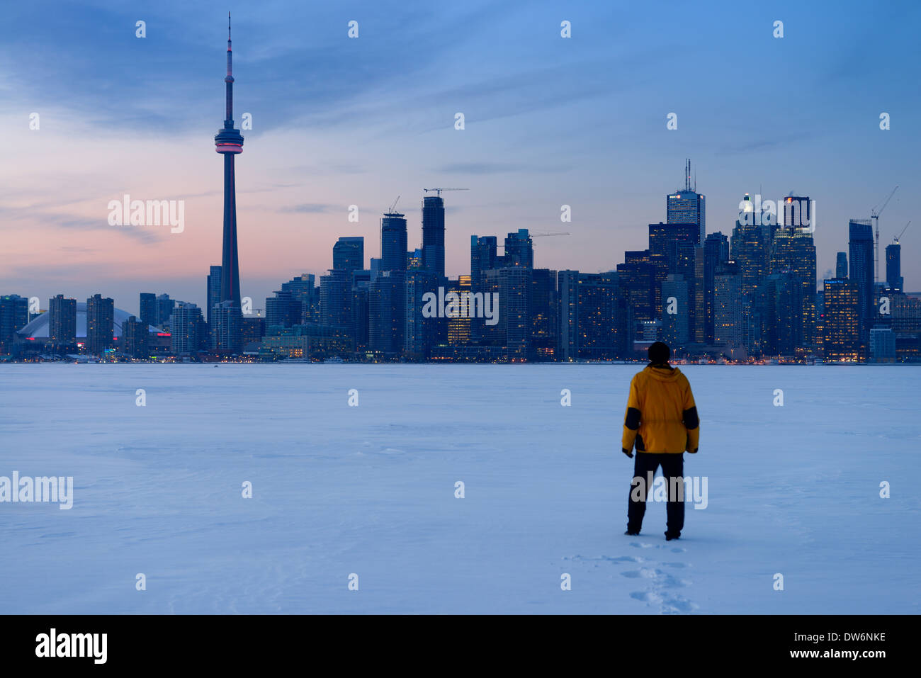 Man walking in fresh snow on frozen Lake Ontario with Toronto city skyline in winter Stock Photo
