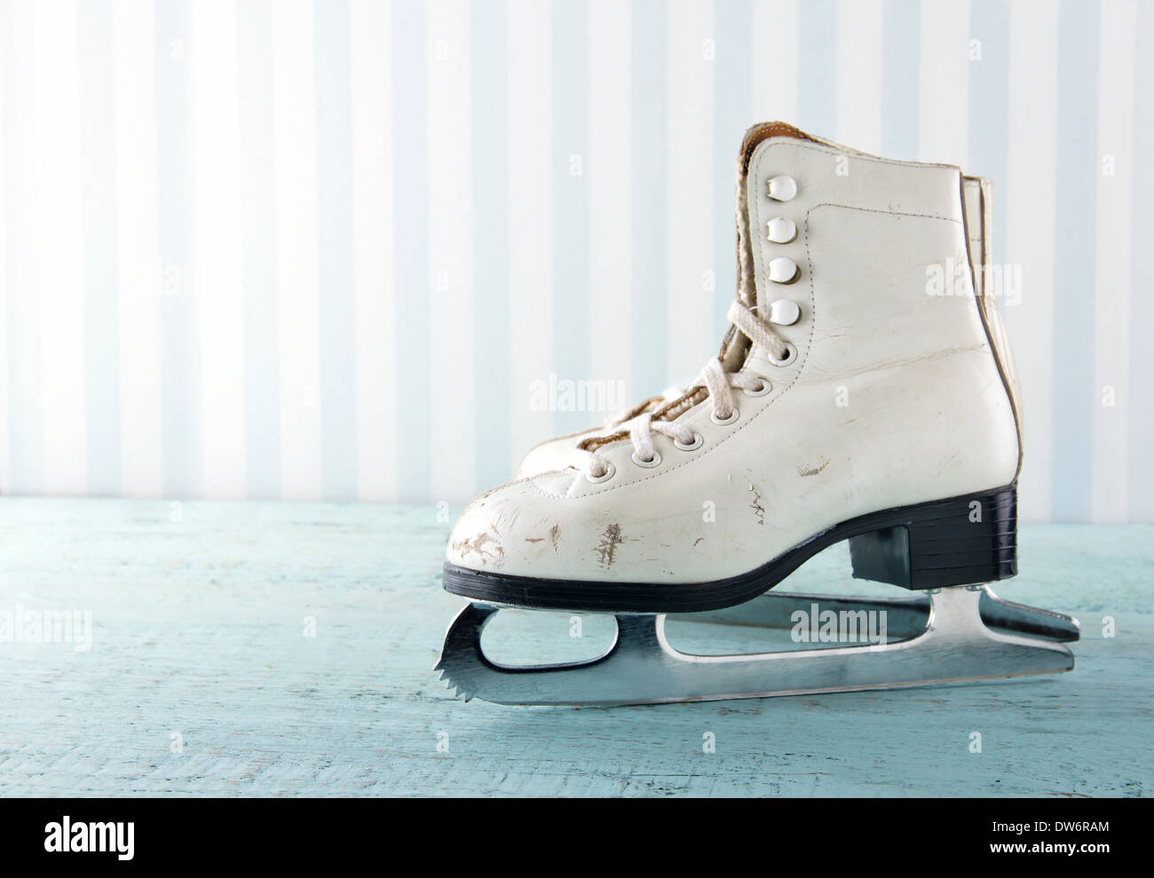 Pair of white women's ice skates on blue vintage wooden background - feminine winter sports concept Stock Photo