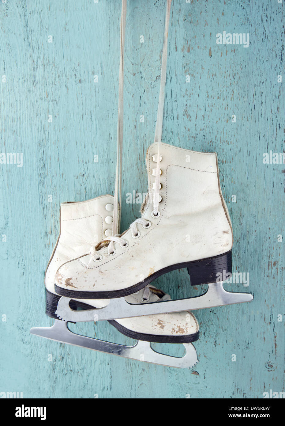 Pair of white women's ice skates on blue vintage wooden background - feminine winter sports concept Stock Photo