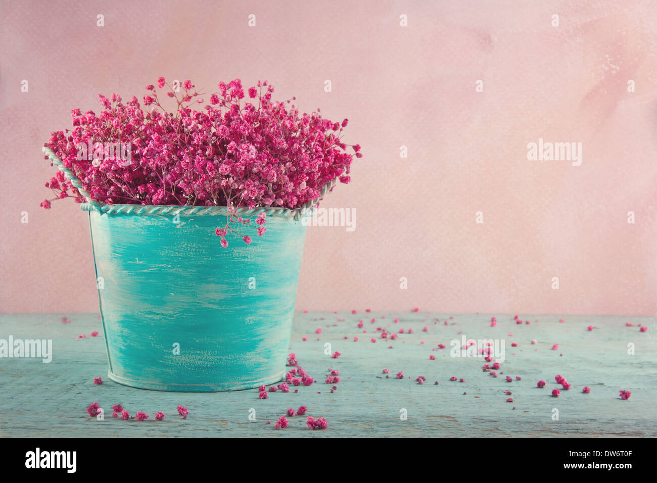 Pink dried baby's breath flowers in a blue vase on wooden vintage