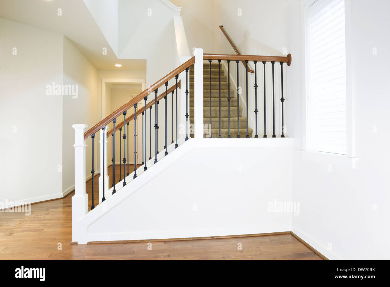Horizontal photo of residential hard wooden floors and custom staircase made of iron and wood railing with carpet on steps Stock Photo