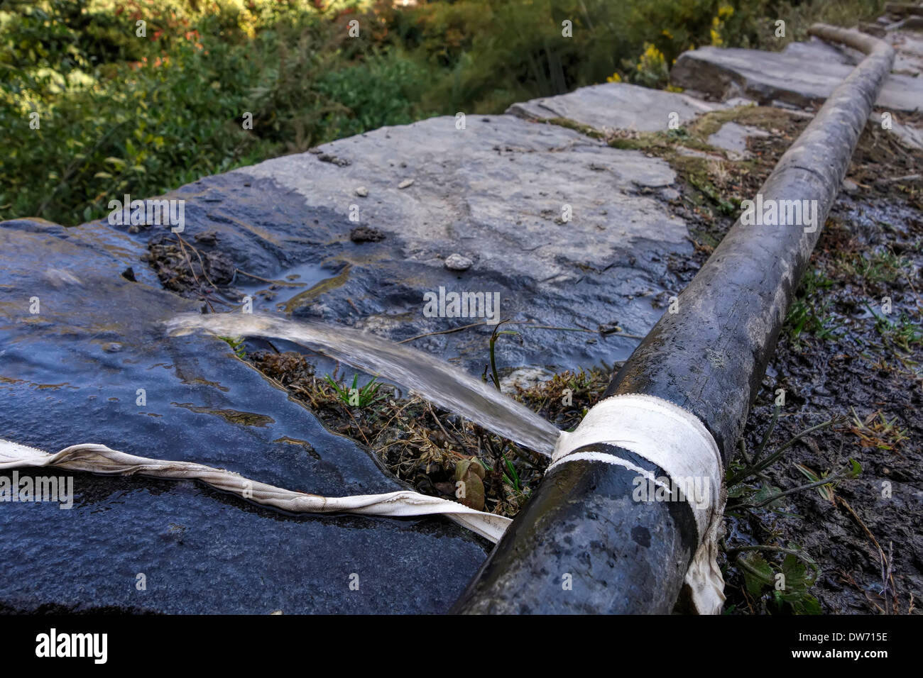Leaking water pipe along the Annapurna road near the village of Dharapani, Nepal. Stock Photo