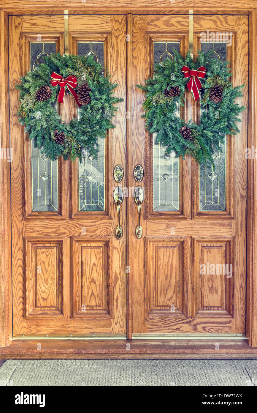 Two Christmas wreaths hanging from a double front door Stock Photo - Alamy