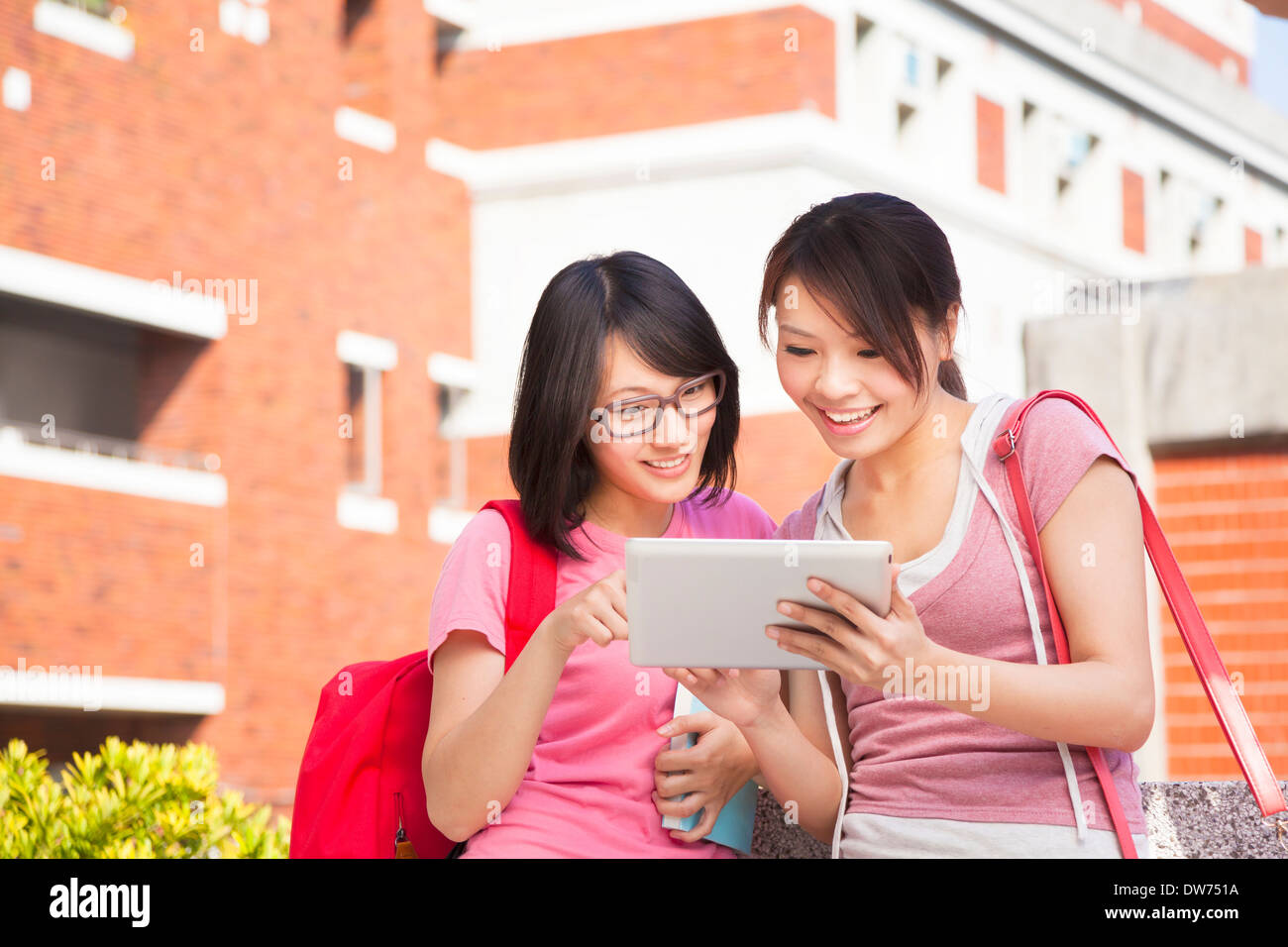 two students using a tablet to discuss homework at campus Stock Photo