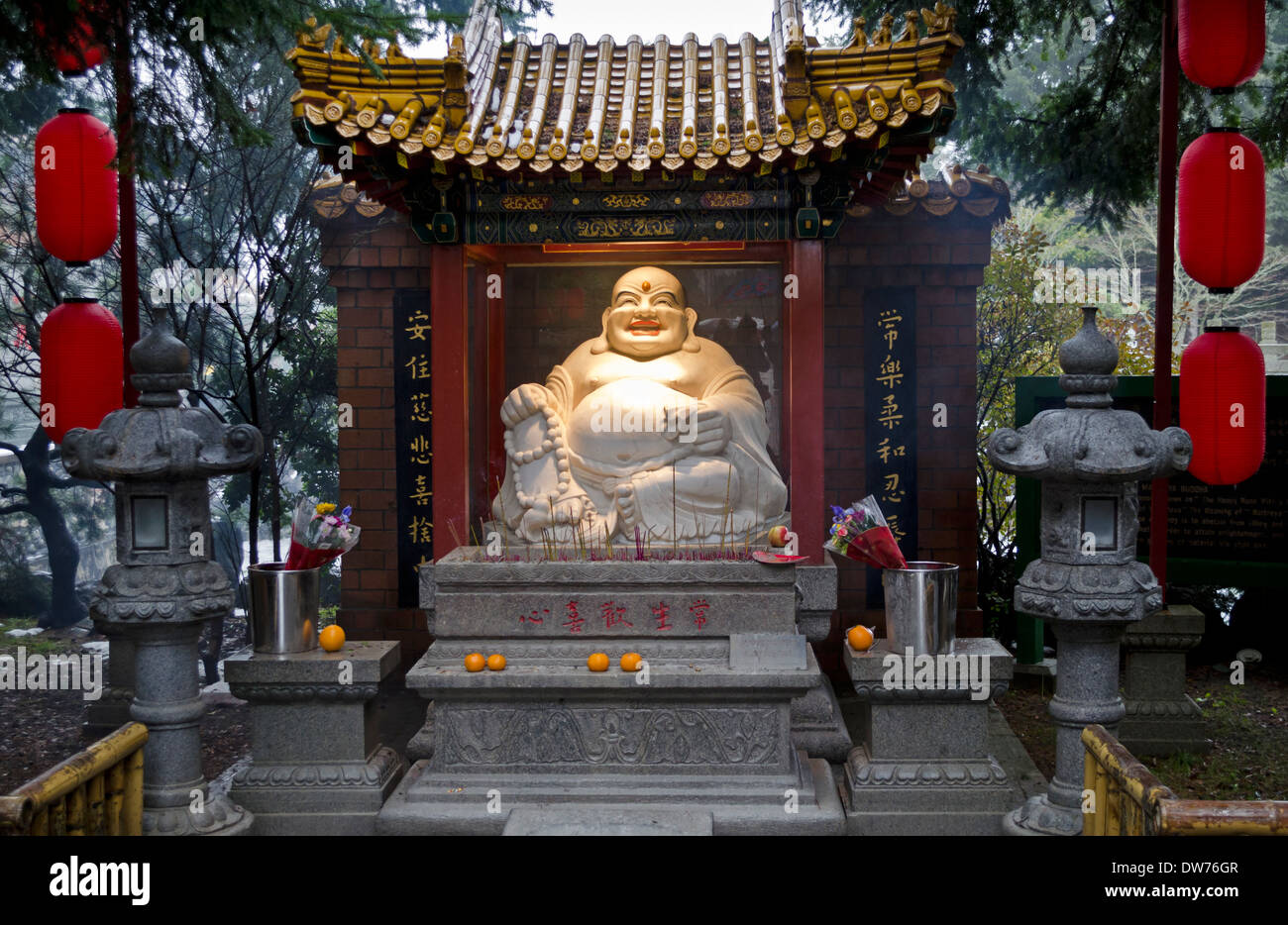 Smiling Laughing Buddha statue with incense and offerings at