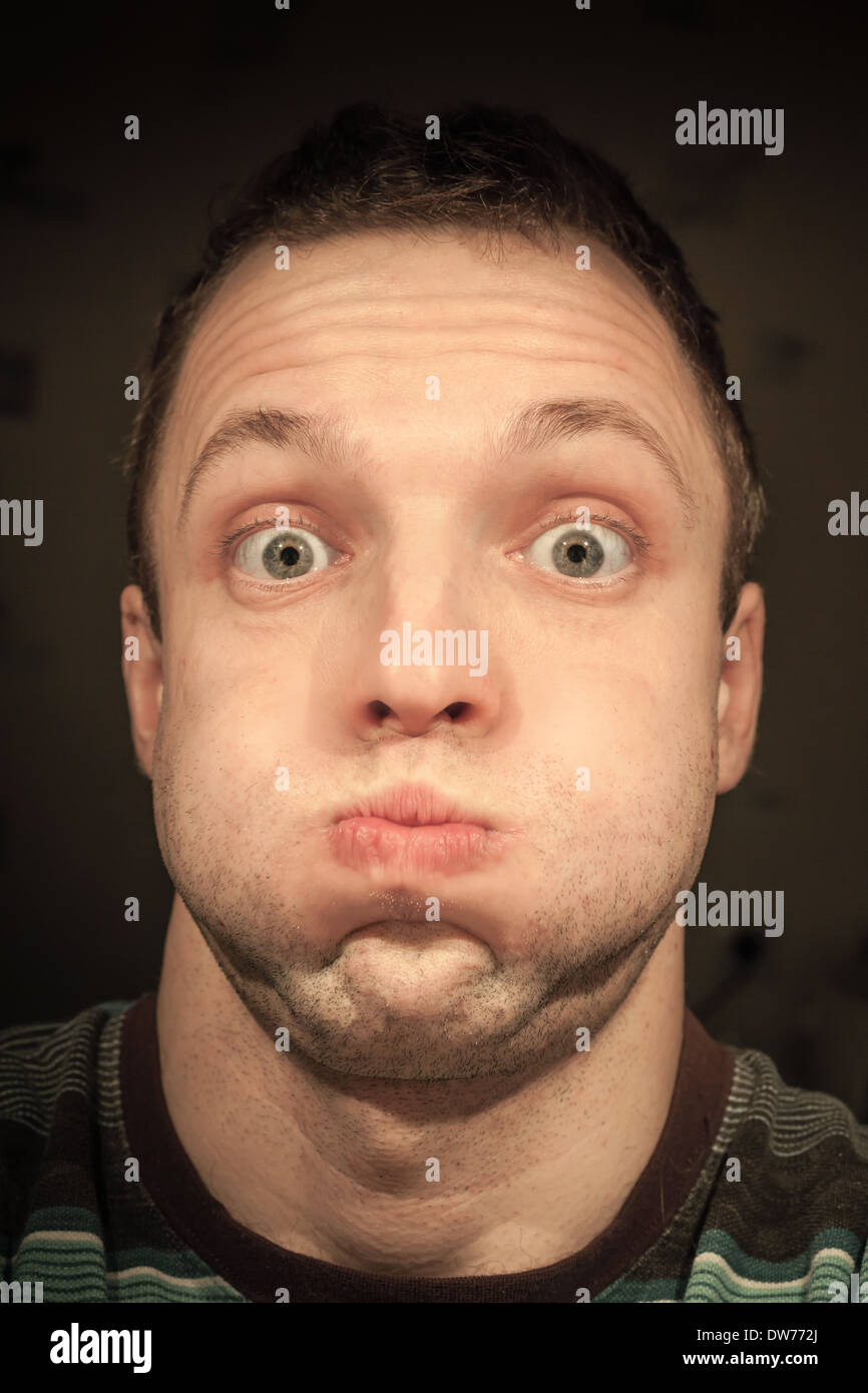 Young funny Caucasian man inflates cheeks. Closeup portrait Stock Photo