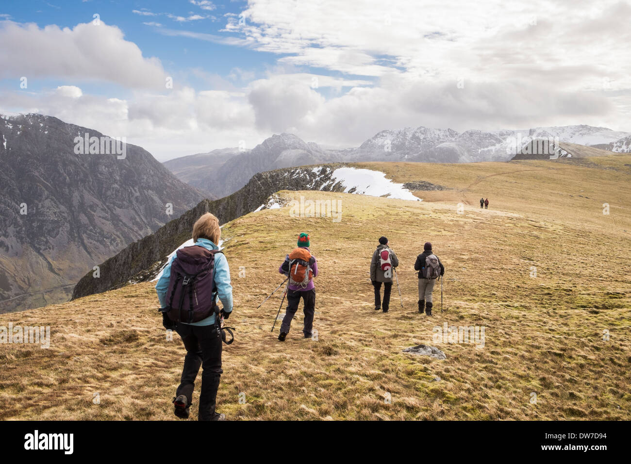 Group of Ramblers hiking to Mynydd Perfedd on Marchlyn horseshoe with distant peaks in mountains of Snowdonia, North Wales, UK Stock Photo