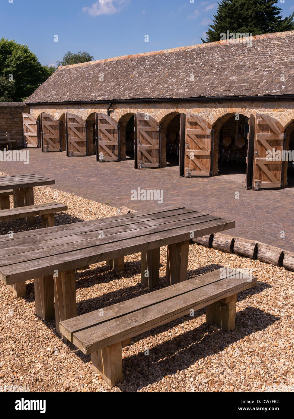Picnic tables and row of arch doorways in old stone stable block, Fineshade Woods, Corby, Northamptonshire, England, UK Stock Photo