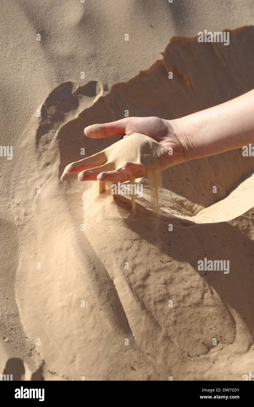 Sand slipping through the fingers of a woman's hand in the desert of
