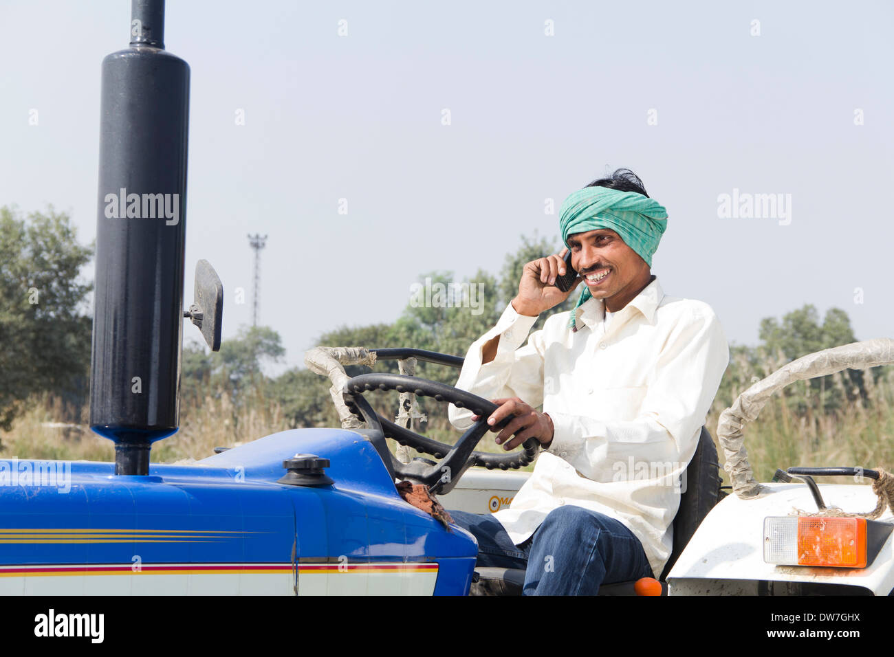 1 indian farmer driving tractor and talking Stock Photo - Alamy