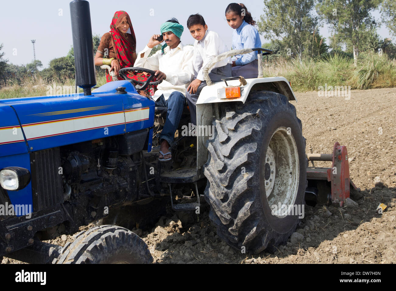 indian farmer driving tractor with family and talking with mobile Stock ...