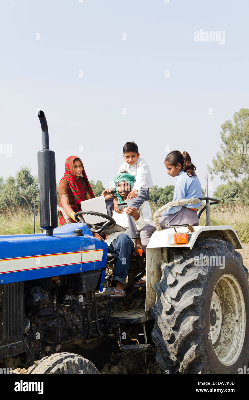Indian farmer driving tractor with family and talking Stock Photo