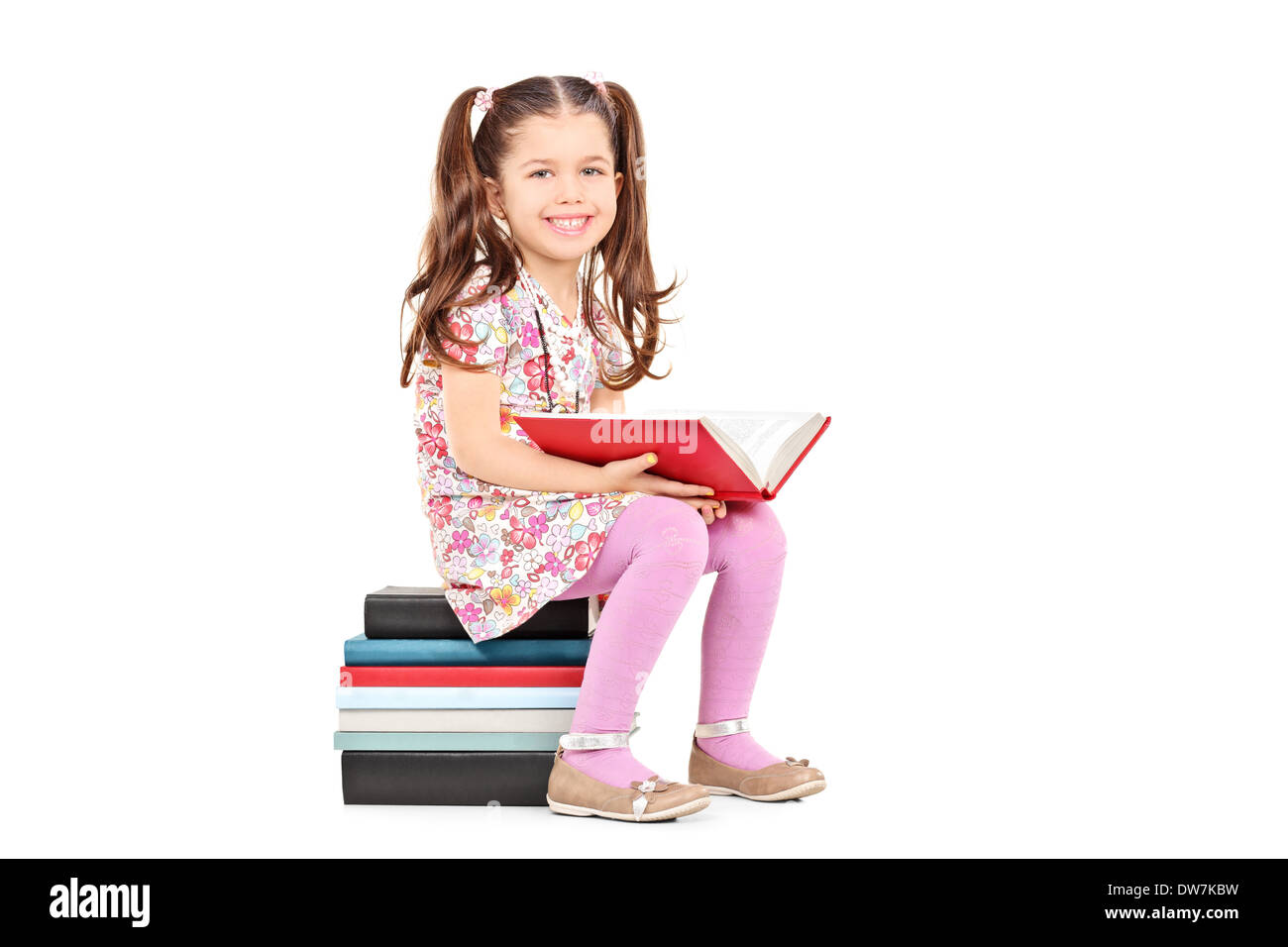 Little girl posing seated on a stack of books Stock Photo - Alamy
