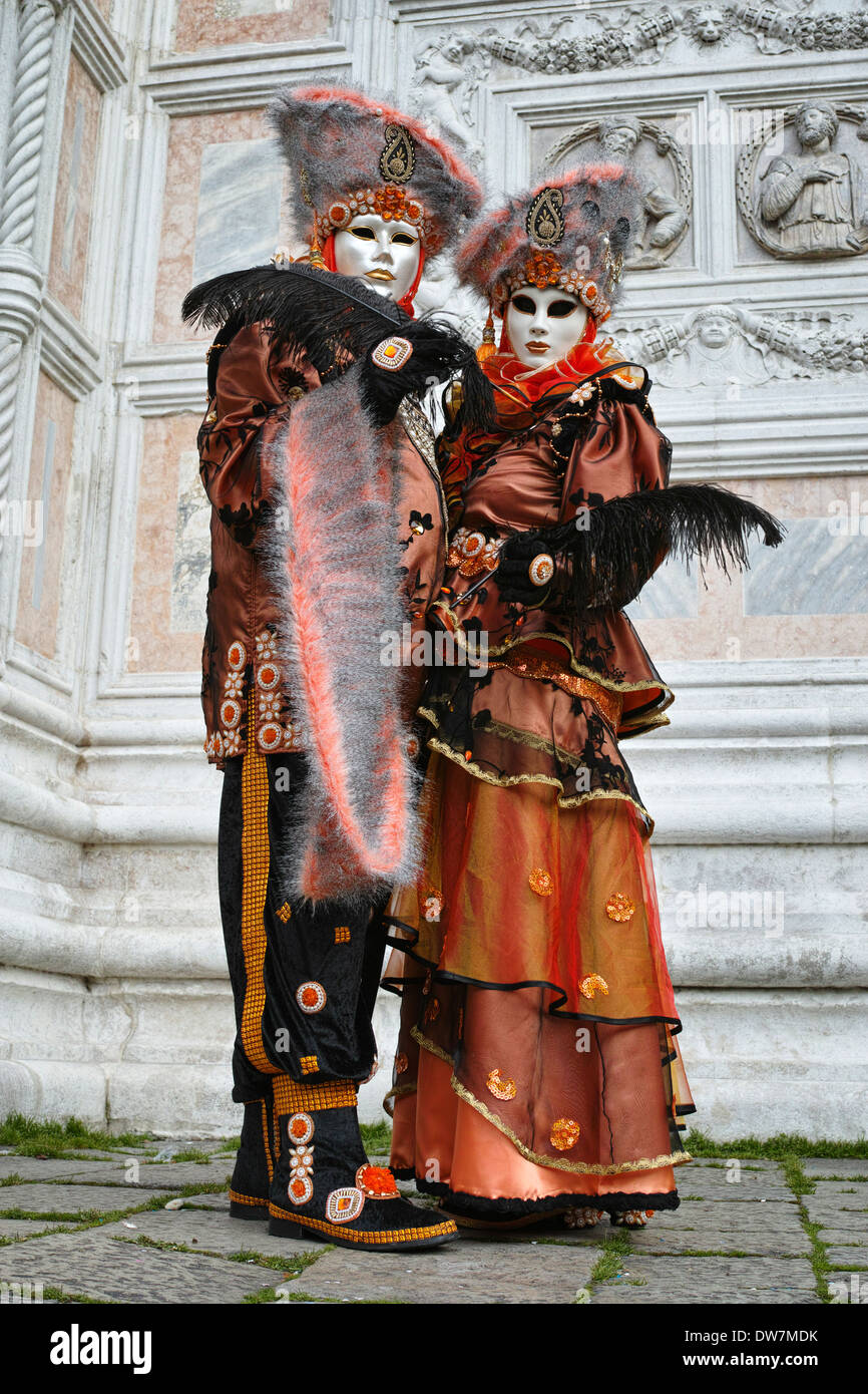 Participants in orange and brown costumes at Venice Carnival, Italy, 2014 Stock Photo