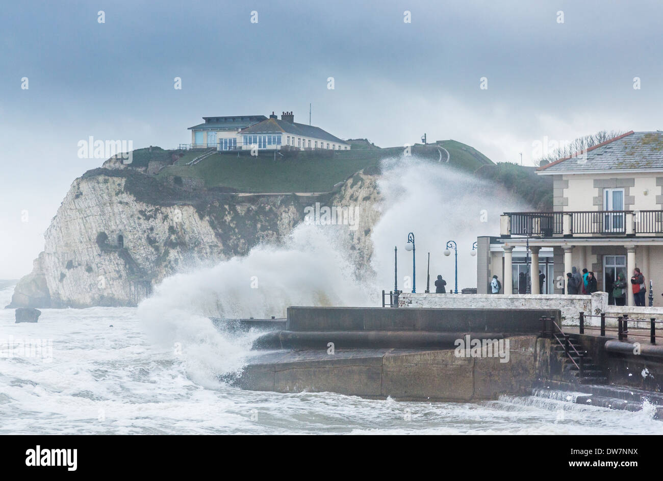 Large waves breaking over the seafront in Freshwater, Isle of Wight during a storm with high winds, people sheltering Stock Photo