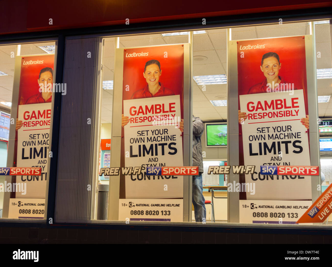 Gamble responsibly posters showing national gambling helpline number in Ladbrokes Bookmakers. Stock Photo
