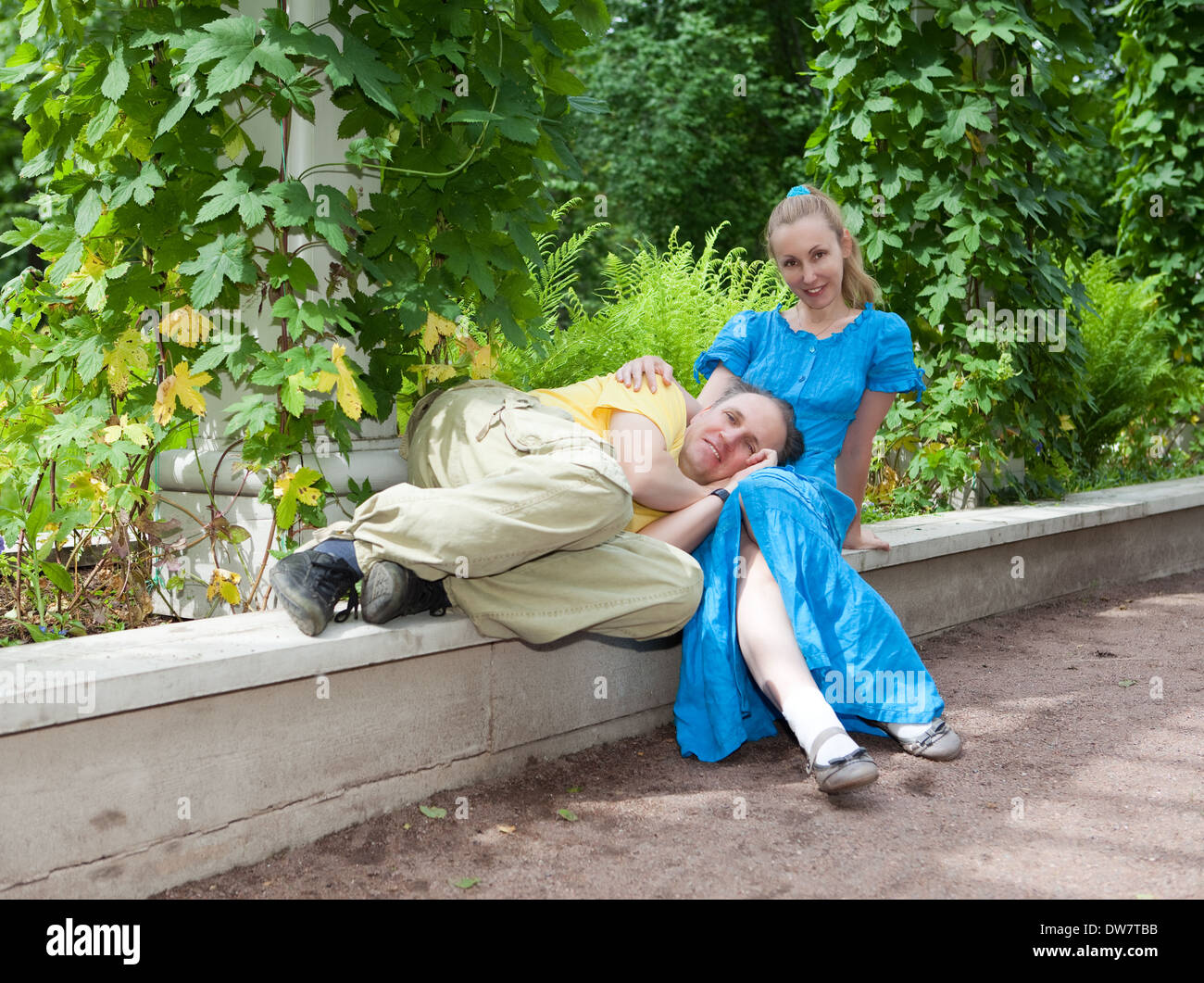Young happy couple sits in the arbour twined greens Stock Photo