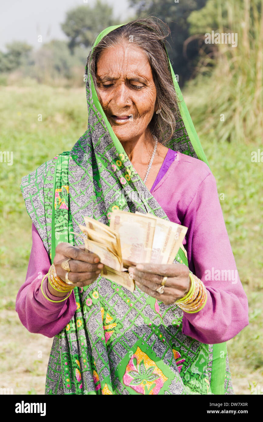 1 Indian woman standing with rupees and counting Stock Photo