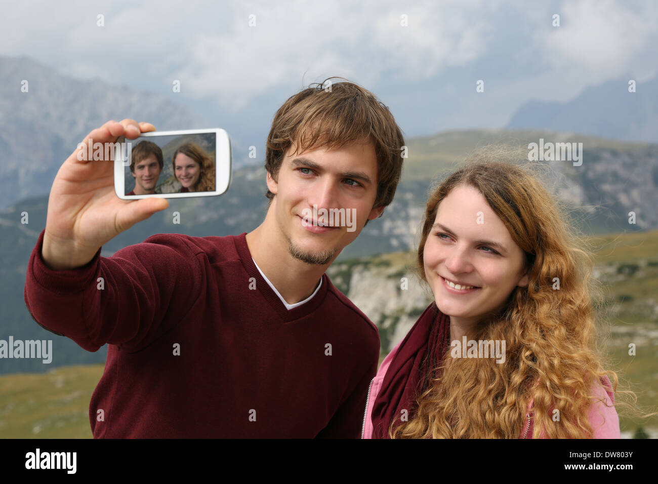 Young couple taking photos with a smartphone during holidays in the mountains Stock Photo