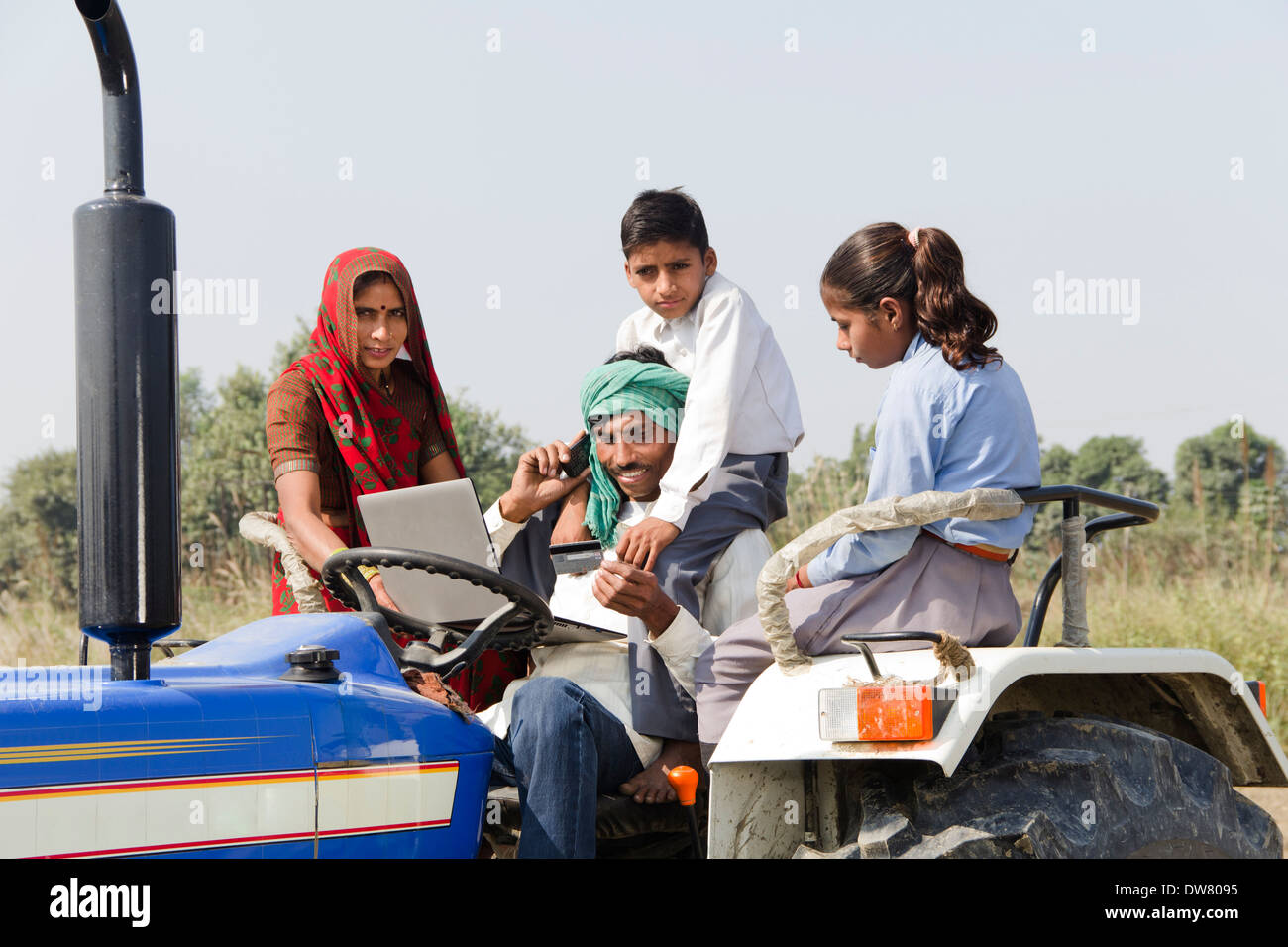 Indian farmer driving tractor with family and talking Stock Photo