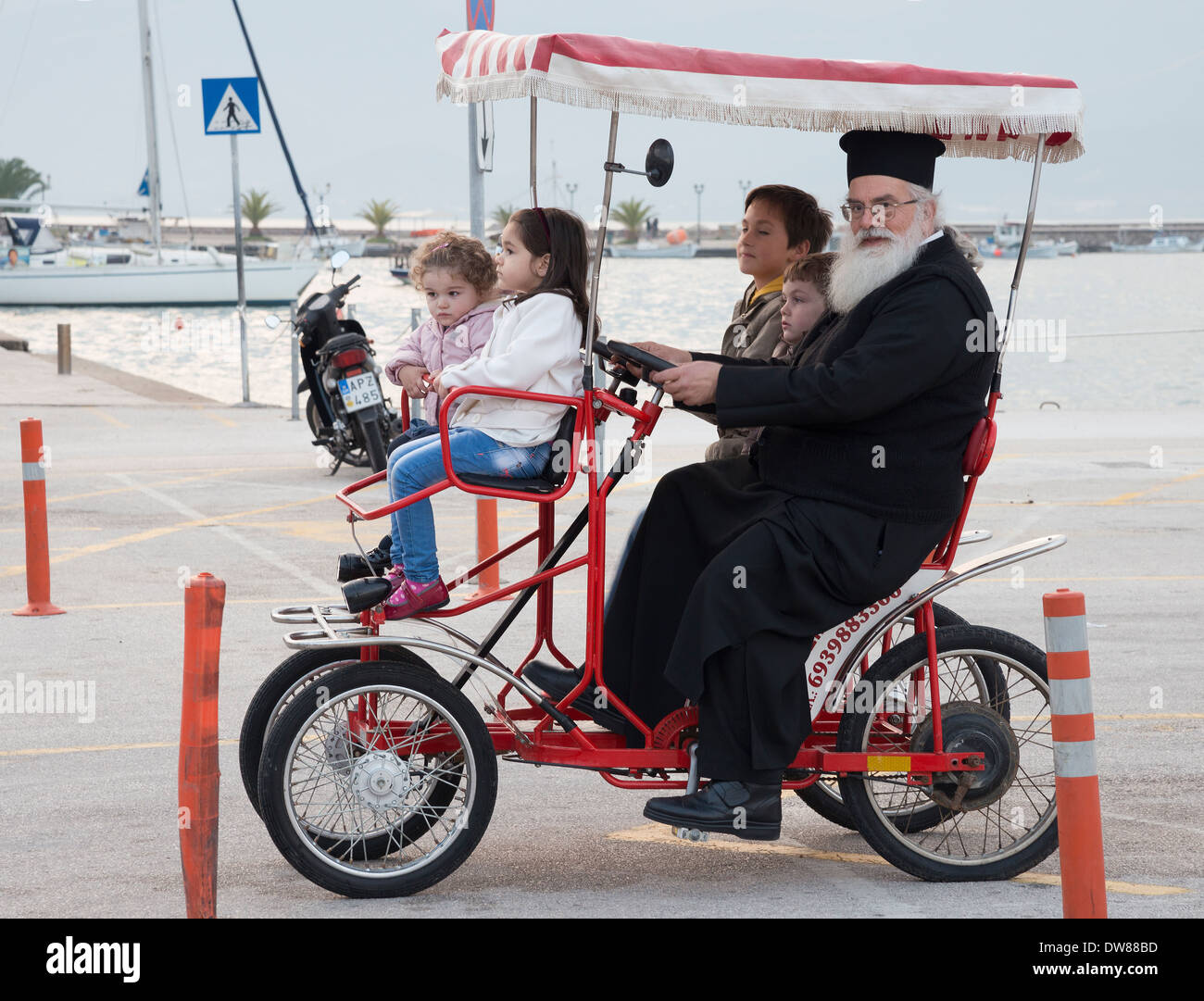 A priest and children on a tourist quadricycle in Nafplio harbour, Argolid, Peloponnese, Greece Stock Photo