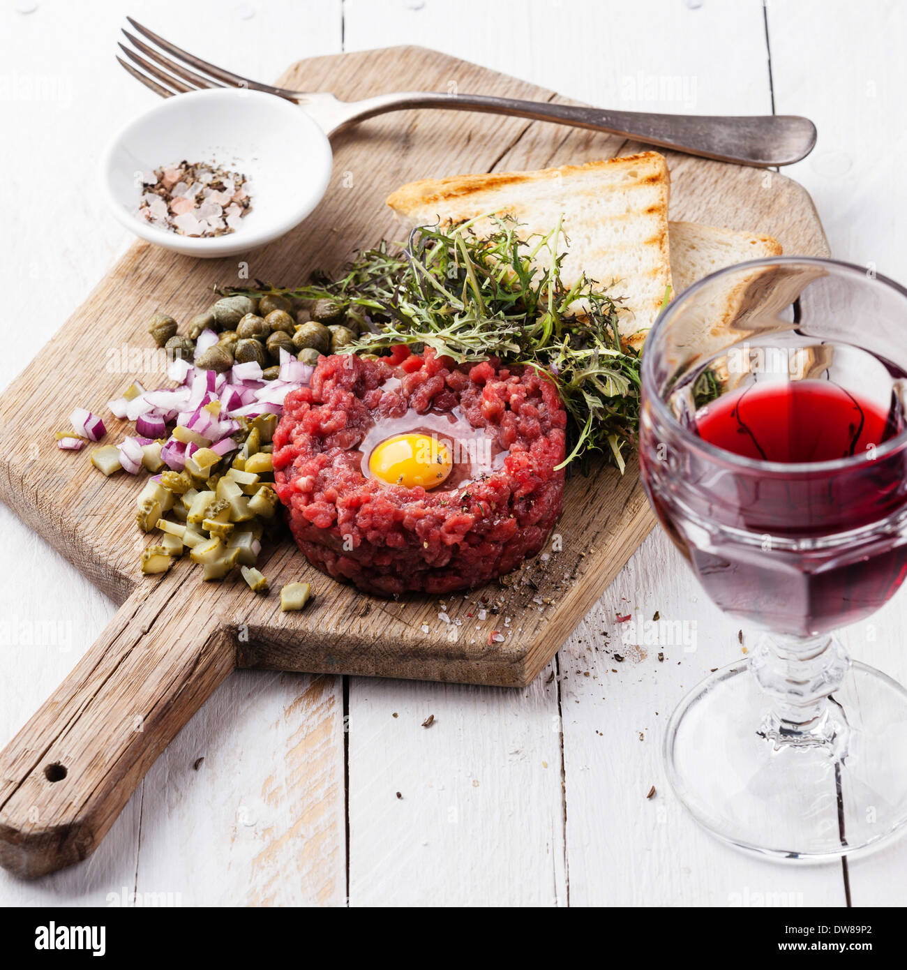 Beef tartare with capers and fresh onion on board with wine Stock Photo